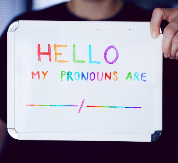 Foto di una lavagna con su scritto "Hello, my pronouns are:"